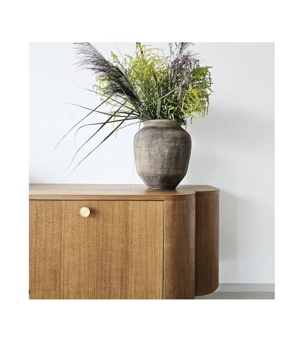 golden brass furniture knob on a wooden chest of drawers door